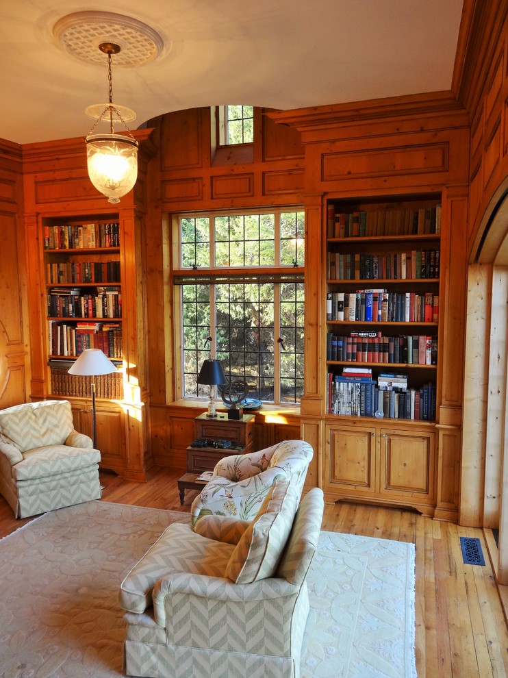 Inredning av ett klassiskt litet separat vardagsrum, med ett bibliotek och ljust trägolv