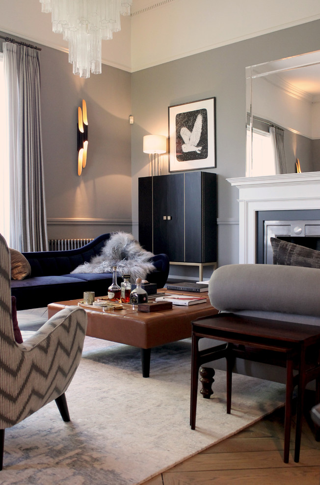 Cette photo montre un salon tendance avec un mur gris, un sol en bois brun, une cheminée standard, un manteau de cheminée en métal et un sol marron.