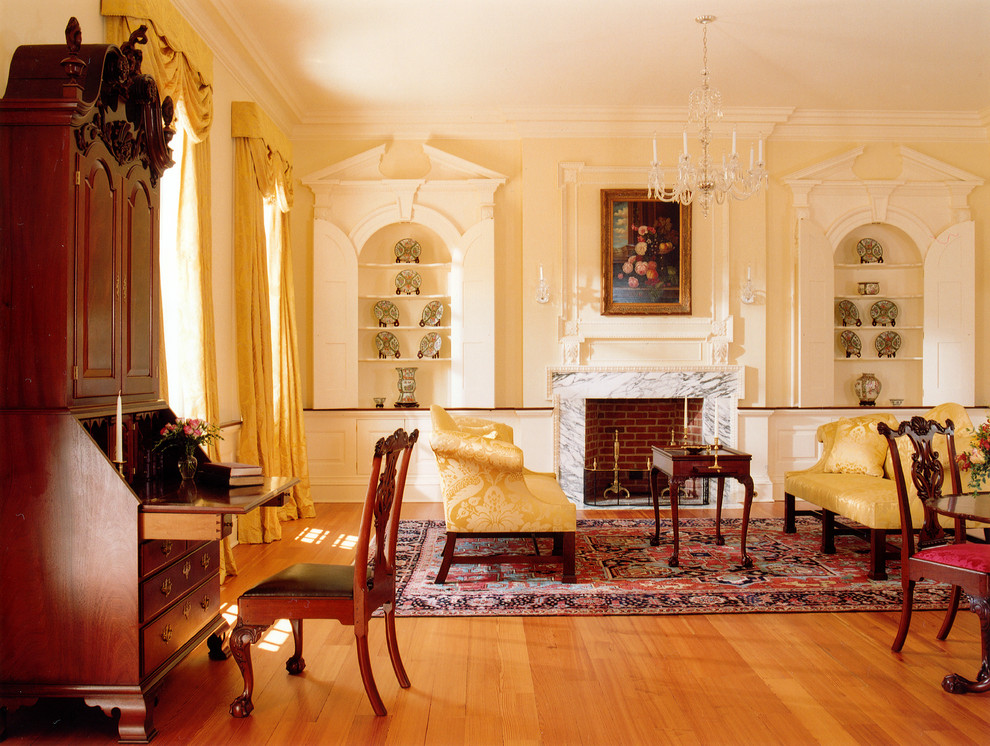 Modelo de salón para visitas cerrado clásico con paredes amarillas, suelo de madera en tonos medios, todas las chimeneas y marco de chimenea de piedra