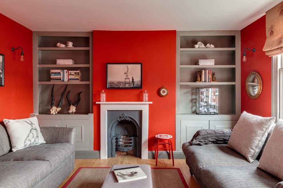 Источник вдохновения для домашнего уюта: парадная гостиная комната в стиле неоклассика (современная классика) с красными стенами, светлым паркетным полом и стандартным камином без телевизора