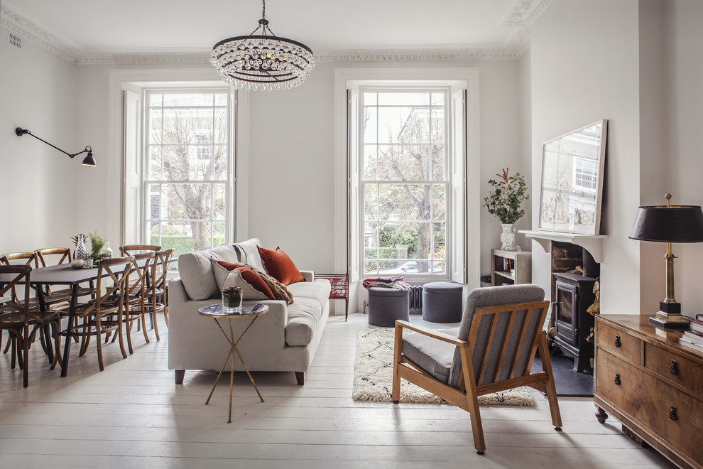 Traditional living room in London with white walls, painted wood flooring, a wood burning stove and no tv.