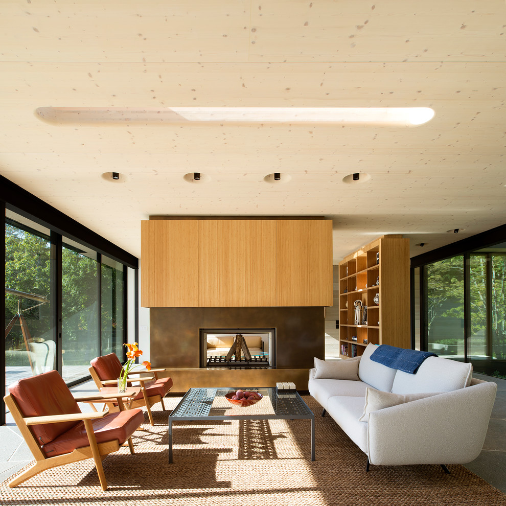 Imagen de salón abierto minimalista de tamaño medio sin televisor con chimenea de doble cara, marco de chimenea de metal y suelo gris