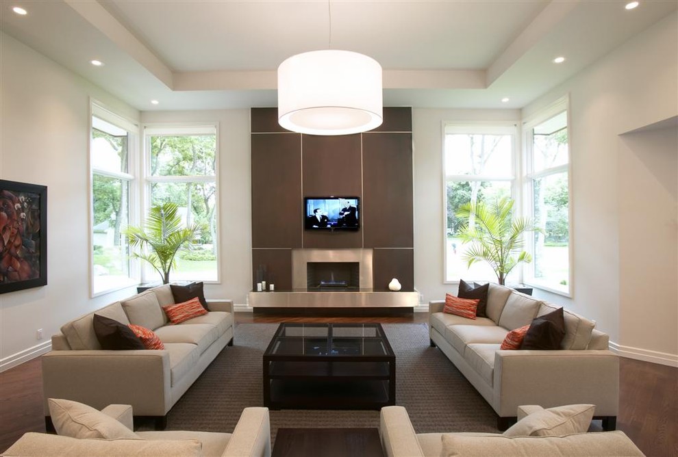 На фото: огромная гостиная комната в современном стиле с белыми стенами, стандартным камином, телевизором на стене и ковром на полу