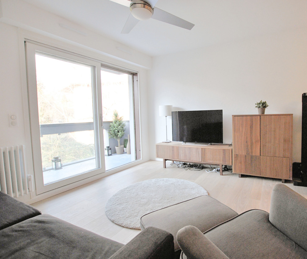 Bild på ett litet funkis separat vardagsrum, med ljust trägolv, vita väggar och en fristående TV