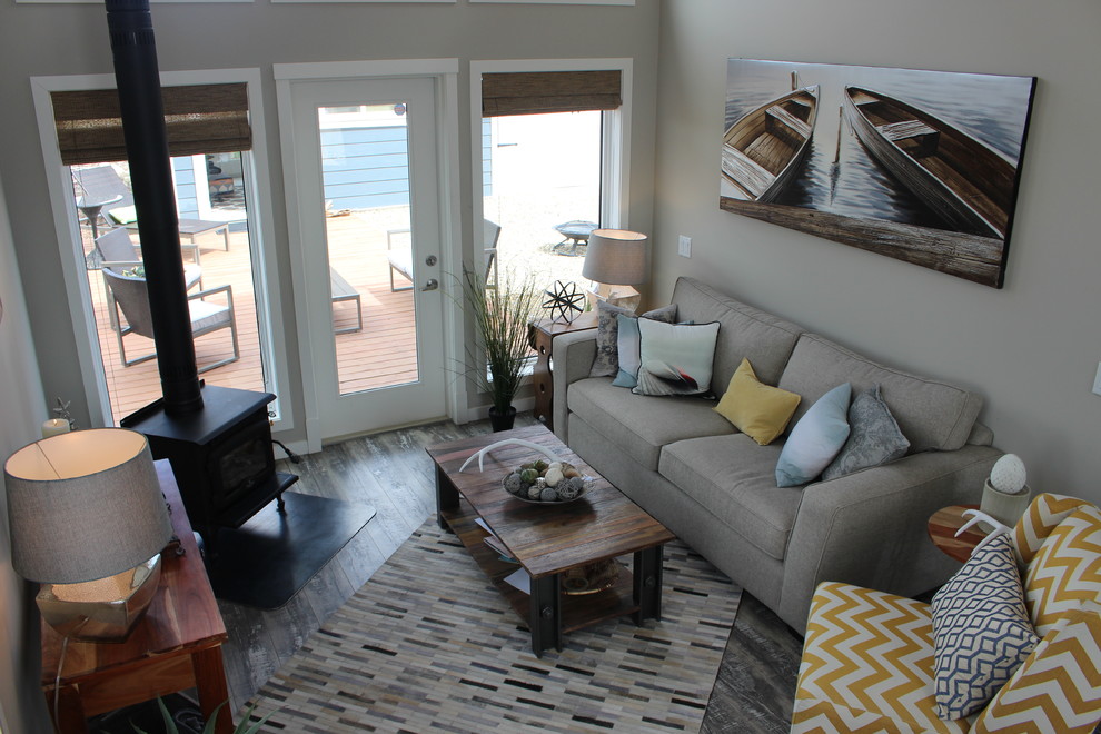 Kleines, Offenes, Repräsentatives Maritimes Wohnzimmer mit grauer Wandfarbe, braunem Holzboden, Kaminofen und Kaminumrandung aus Metall in Calgary