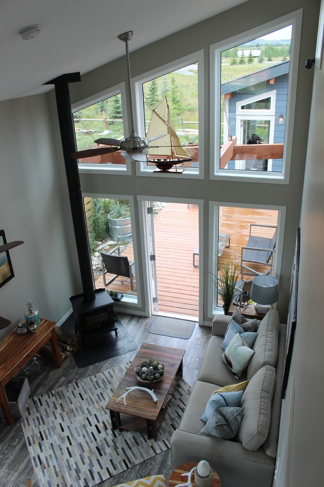 Offenes, Mittelgroßes Maritimes Wohnzimmer mit grauer Wandfarbe, braunem Holzboden, Kaminofen und Kaminumrandung aus Metall in Calgary
