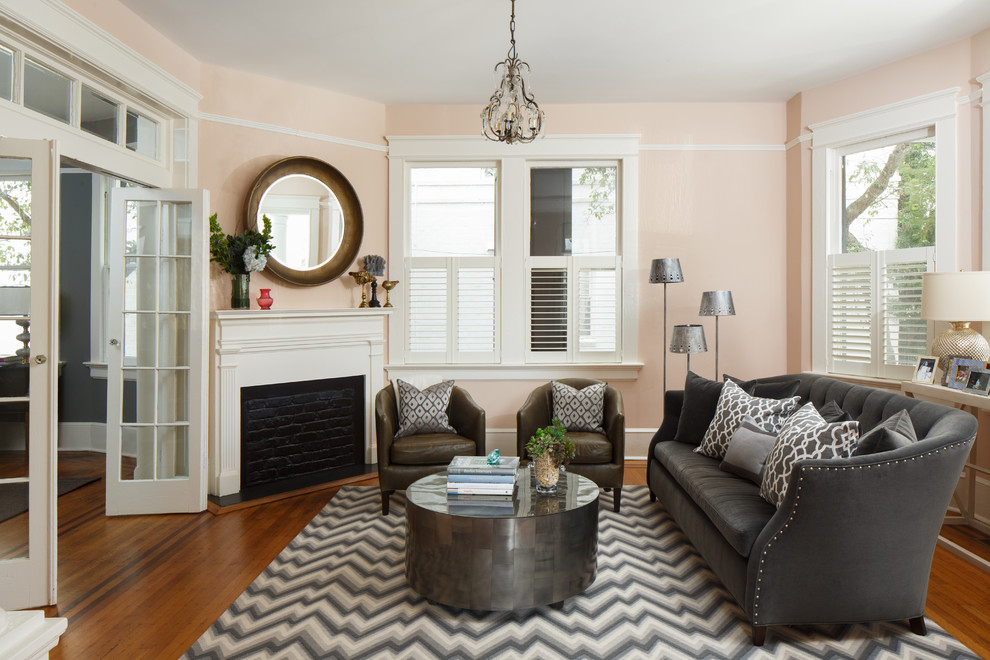Repräsentatives, Abgetrenntes Klassisches Wohnzimmer mit rosa Wandfarbe, braunem Holzboden und verputzter Kaminumrandung in Charleston