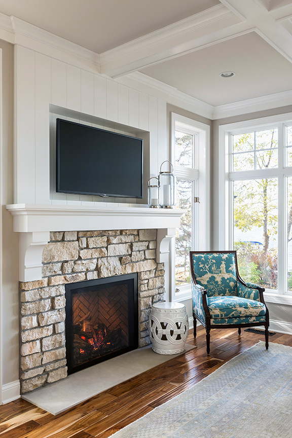 Пример оригинального дизайна: открытая гостиная комната в классическом стиле с серыми стенами, паркетным полом среднего тона, стандартным камином, фасадом камина из камня и телевизором на стене