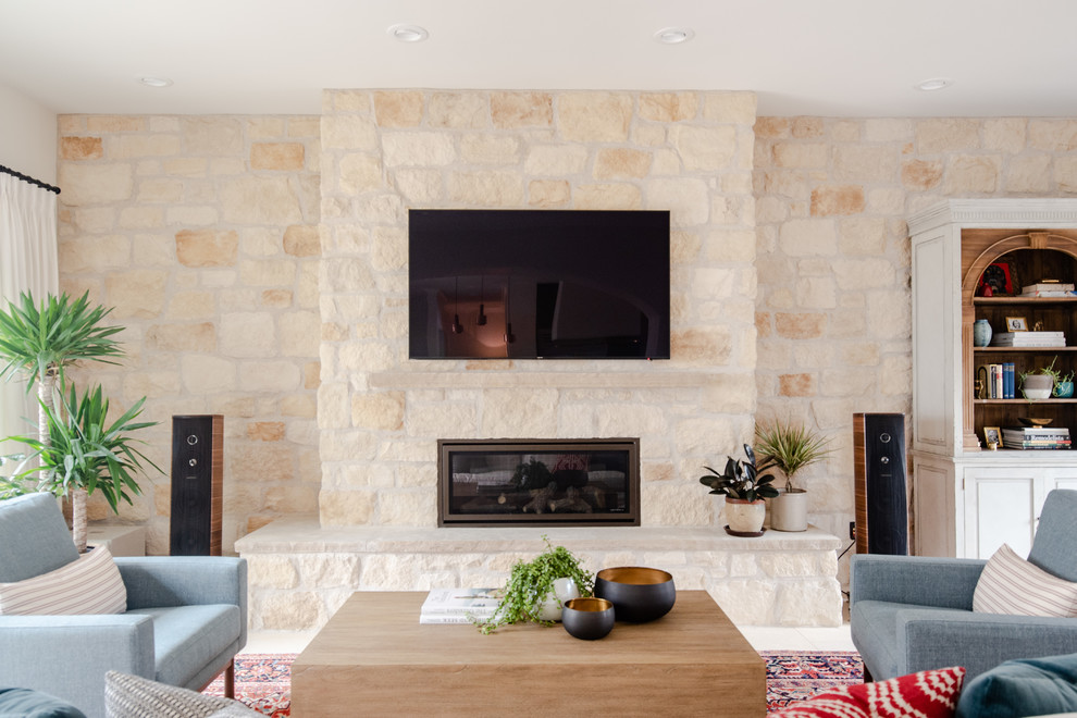 デンバーにあるラグジュアリーな広いコンテンポラリースタイルのおしゃれな独立型リビング (ベージュの壁、石材の暖炉まわり、壁掛け型テレビ、ベージュの床、セラミックタイルの床、横長型暖炉) の写真