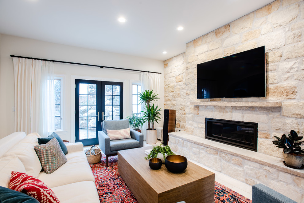 Источник вдохновения для домашнего уюта: большая открытая гостиная комната в современном стиле с белыми стенами, горизонтальным камином, фасадом камина из камня, телевизором на стене, полом из известняка и бежевым полом
