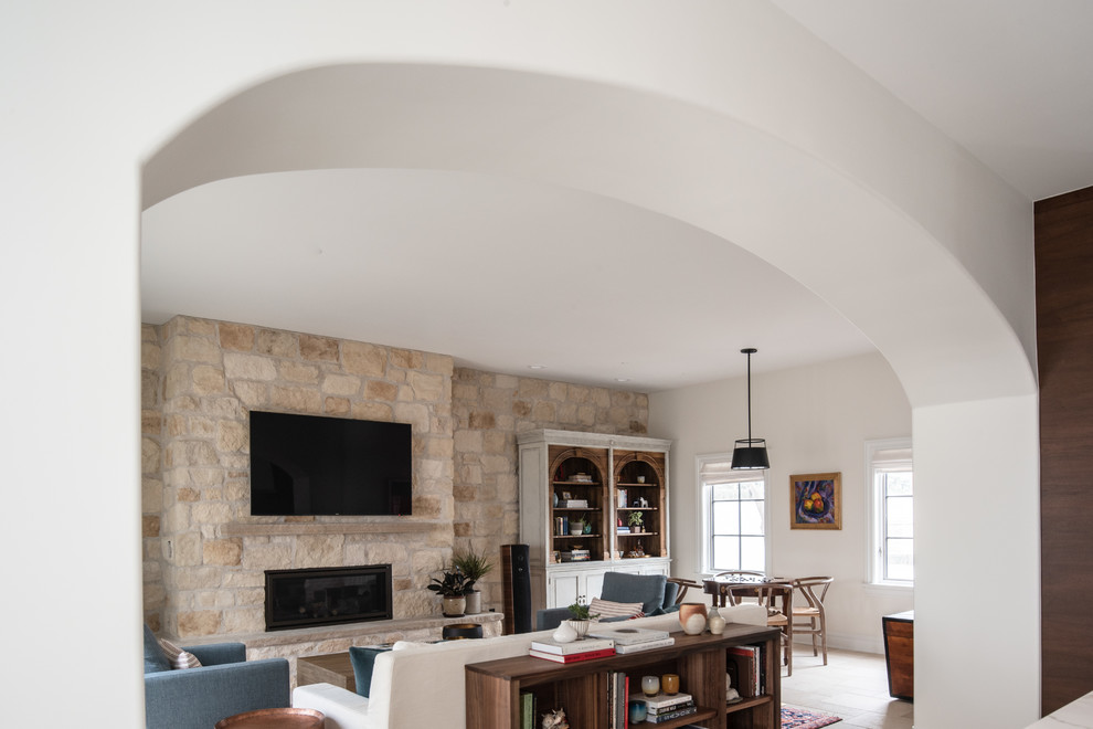 デンバーにあるラグジュアリーな広いコンテンポラリースタイルのおしゃれなリビング (白い壁、ライムストーンの床、石材の暖炉まわり、壁掛け型テレビ、ベージュの床、横長型暖炉) の写真