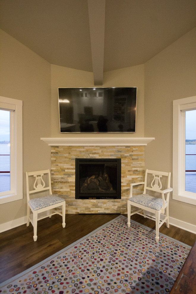 Aménagement d'un petit salon bord de mer ouvert avec un mur gris, un sol en vinyl, une cheminée d'angle, un manteau de cheminée en pierre et un téléviseur fixé au mur.