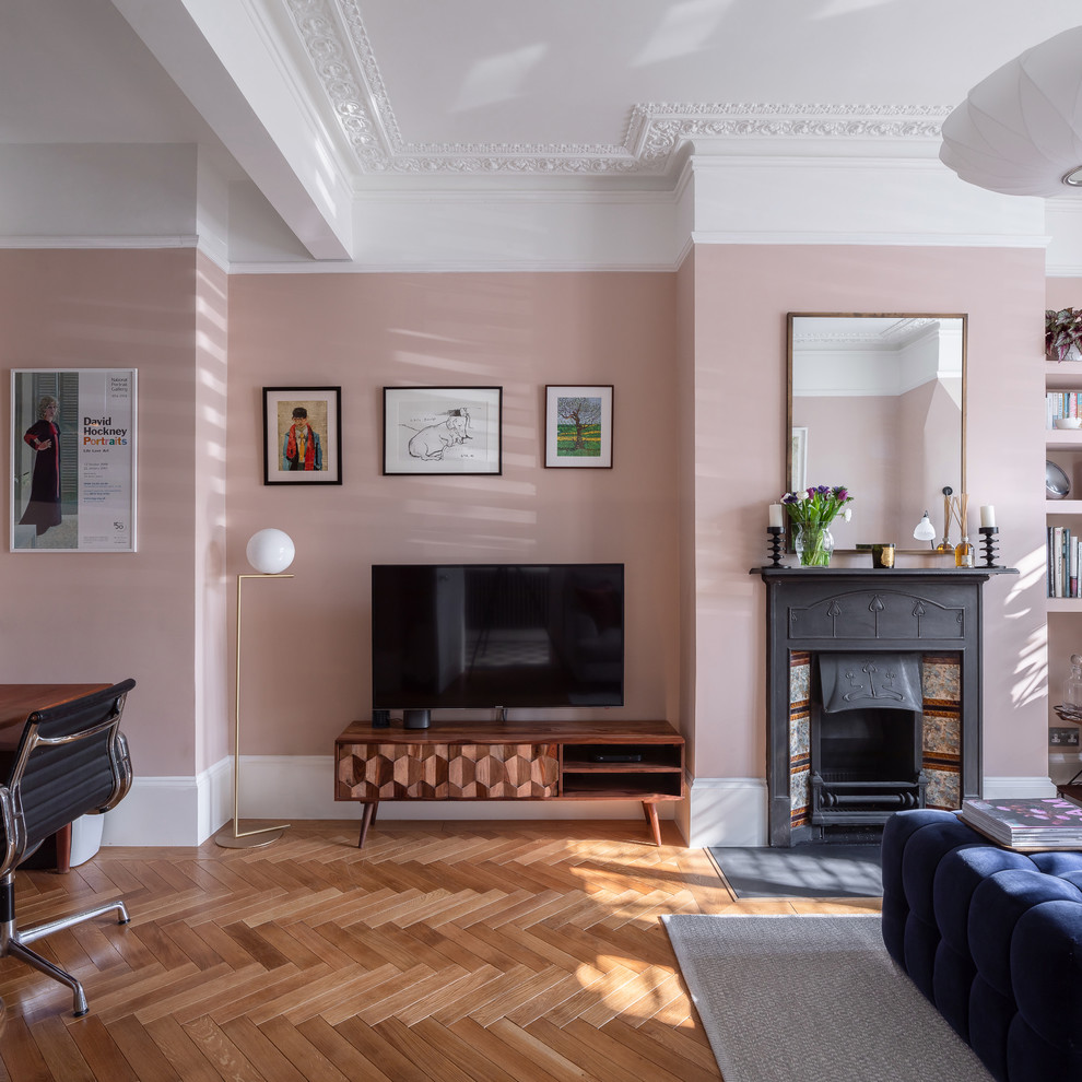 Medium sized classic grey and pink living room in London with pink walls, medium hardwood flooring, a standard fireplace, a tiled fireplace surround, a wall mounted tv, brown floors and a chimney breast.