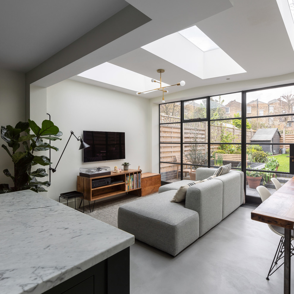 Idee per un soggiorno design di medie dimensioni e aperto con pavimento in cemento, pavimento grigio, pareti bianche e TV a parete