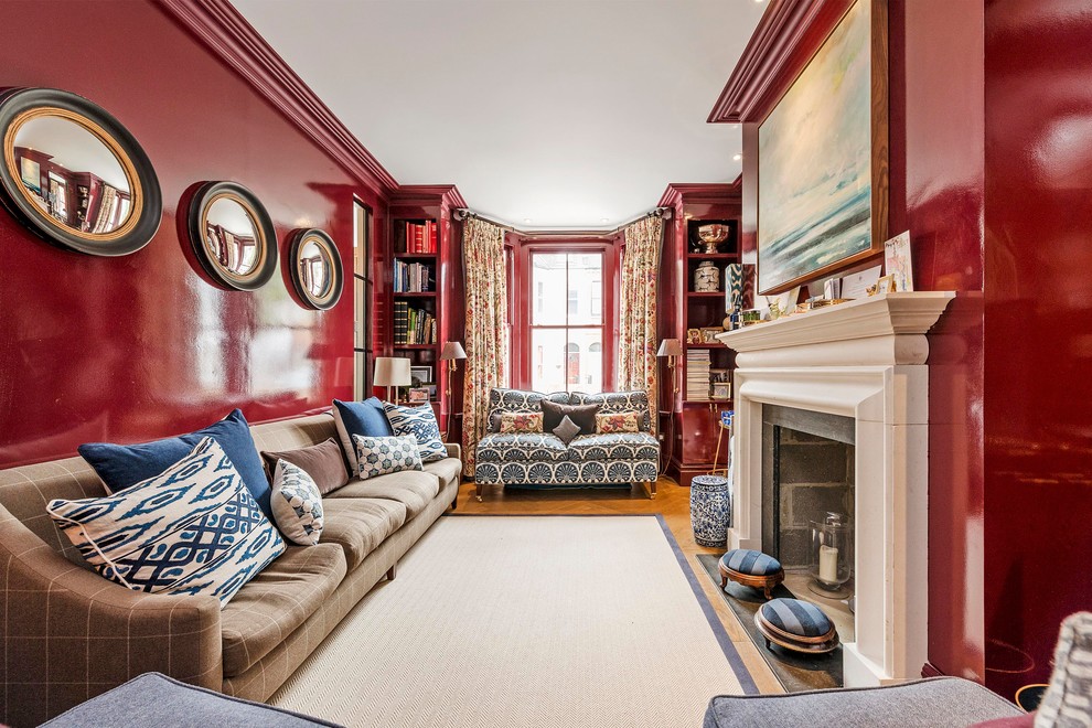 Ispirazione per un soggiorno tradizionale di medie dimensioni con pareti rosse, pavimento in legno massello medio, camino classico e libreria