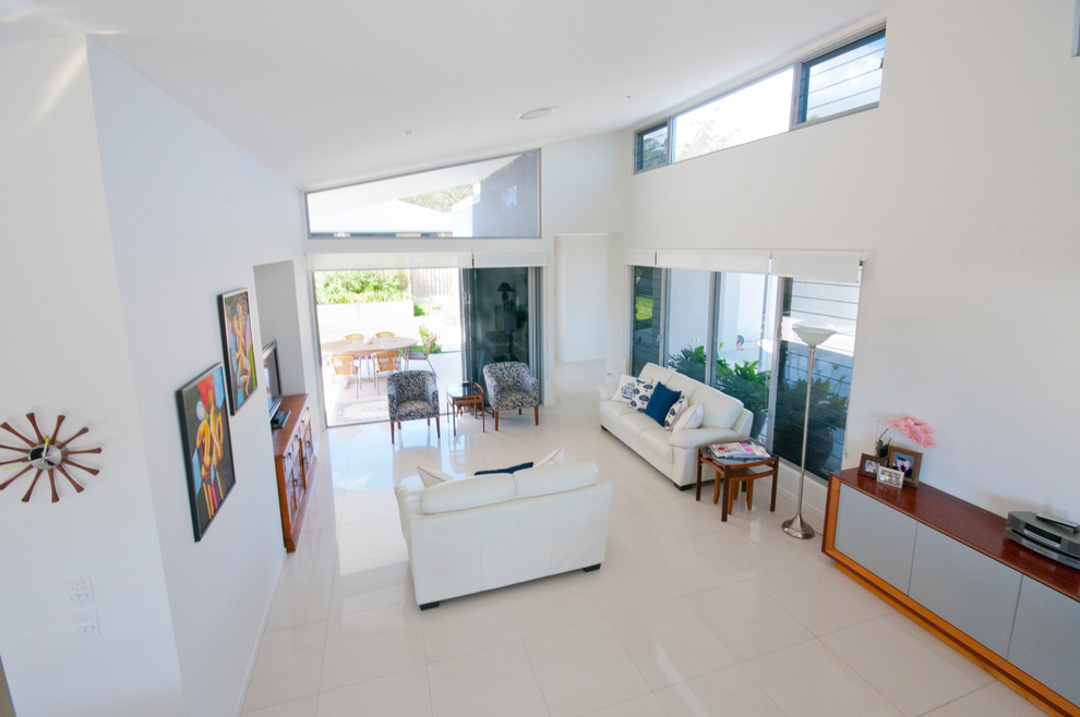 Mittelgroßes, Offenes Modernes Wohnzimmer mit weißer Wandfarbe, Porzellan-Bodenfliesen und freistehendem TV in Brisbane
