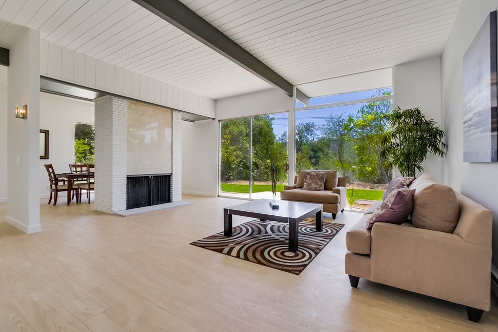 Идея дизайна: открытая гостиная комната в современном стиле с серыми стенами, полом из ламината, стандартным камином и фасадом камина из кирпича