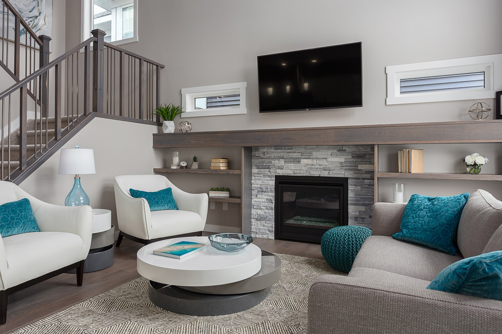 This is an example of a contemporary formal open plan living room in Edmonton with grey walls, dark hardwood flooring, a standard fireplace, a stone fireplace surround, a wall mounted tv and brown floors.