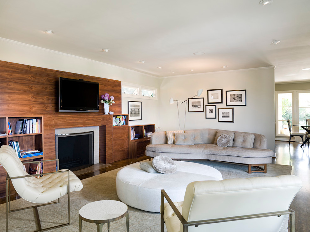 Immagine di un grande soggiorno moderno con pareti beige, camino classico e TV a parete
