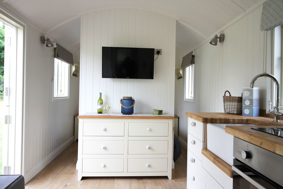 Diseño de salón abierto campestre pequeño con paredes blancas, suelo de madera clara y suelo marrón