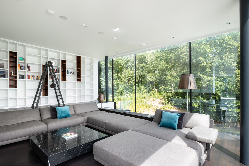 Foto di un soggiorno design con libreria, pareti bianche e pavimento marrone