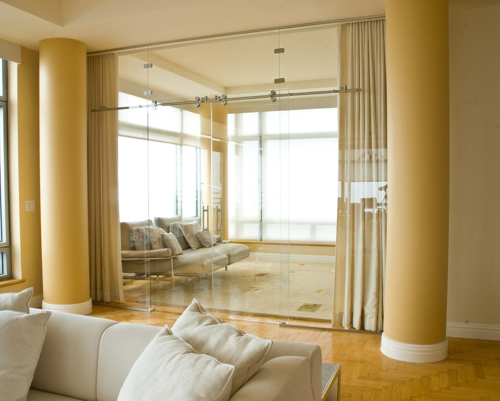 Modelo de salón cerrado moderno extra grande con paredes amarillas y suelo de madera clara