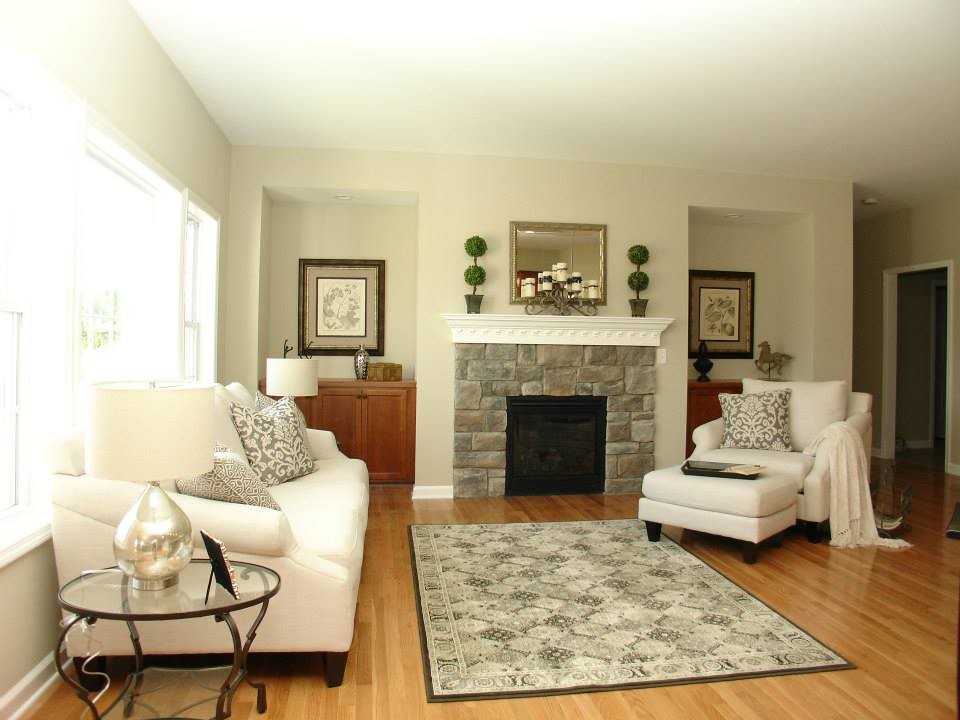 Foto de salón abierto tradicional de tamaño medio con paredes beige, suelo de madera clara, todas las chimeneas y marco de chimenea de piedra