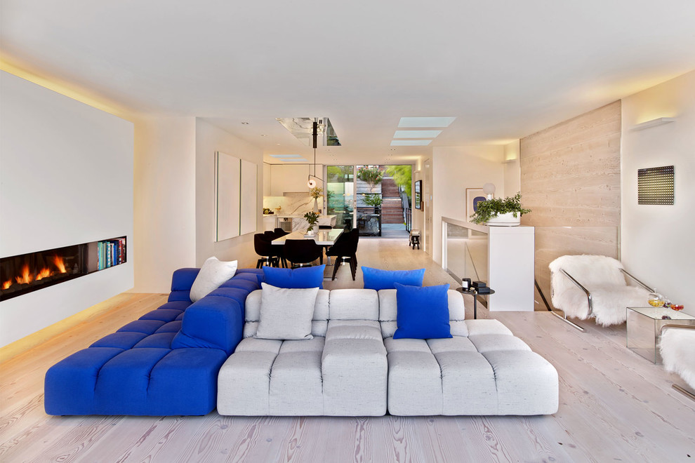 Trendy open concept light wood floor living room photo in San Francisco with yellow walls and a hanging fireplace