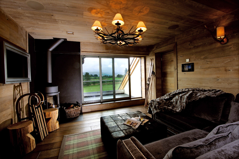 Immagine di un piccolo soggiorno design chiuso con libreria, pareti marroni, cornice del camino in pietra, TV nascosta e stufa a legna