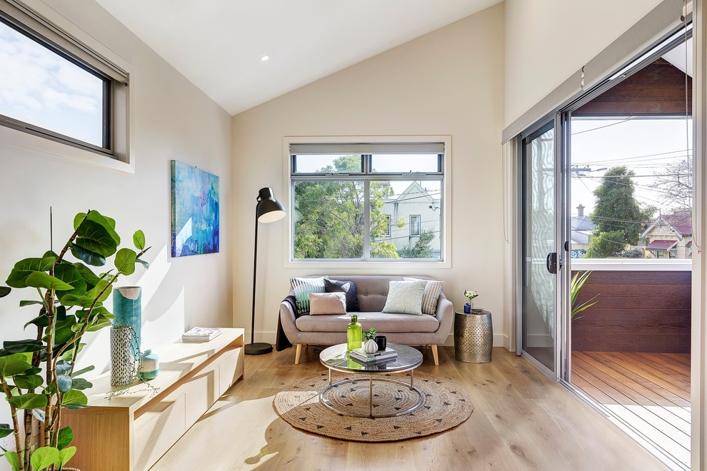 Skandinavisches Wohnzimmer mit beiger Wandfarbe, hellem Holzboden und beigem Boden in Melbourne