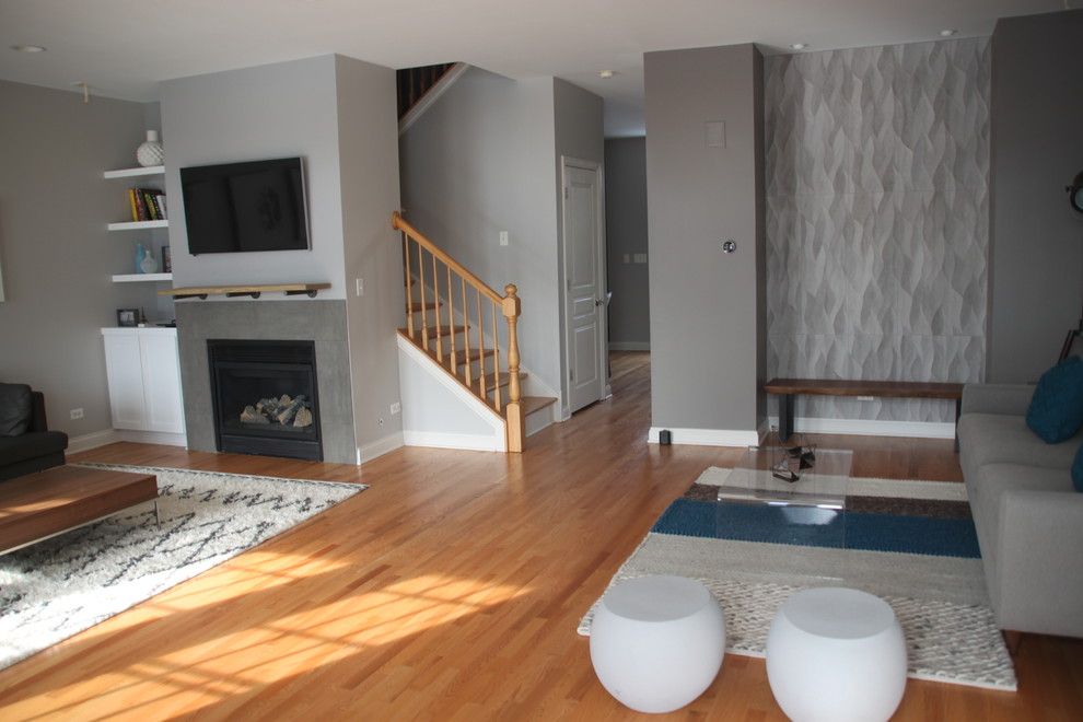 Стильный дизайн: гостиная комната в современном стиле с серыми стенами, светлым паркетным полом, стандартным камином, фасадом камина из бетона и телевизором на стене - последний тренд