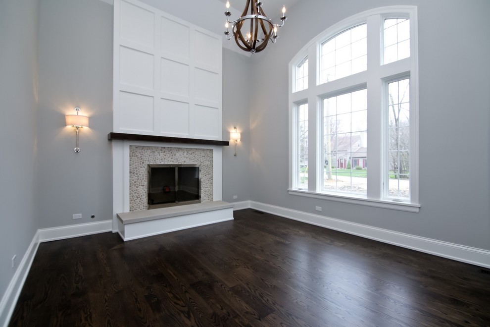 Пример оригинального дизайна: изолированная гостиная комната среднего размера в стиле неоклассика (современная классика) с серыми стенами, темным паркетным полом, стандартным камином, фасадом камина из плитки и коричневым полом