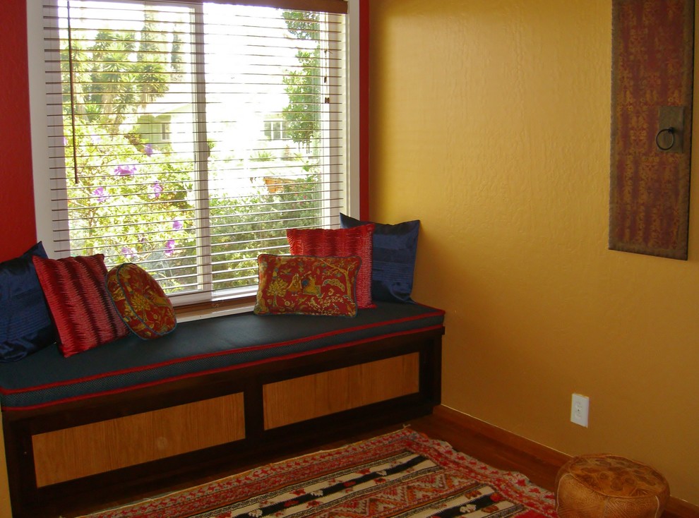 Inredning av ett litet allrum med öppen planlösning, med gula väggar, mellanmörkt trägolv, en standard öppen spis, en spiselkrans i tegelsten och en väggmonterad TV