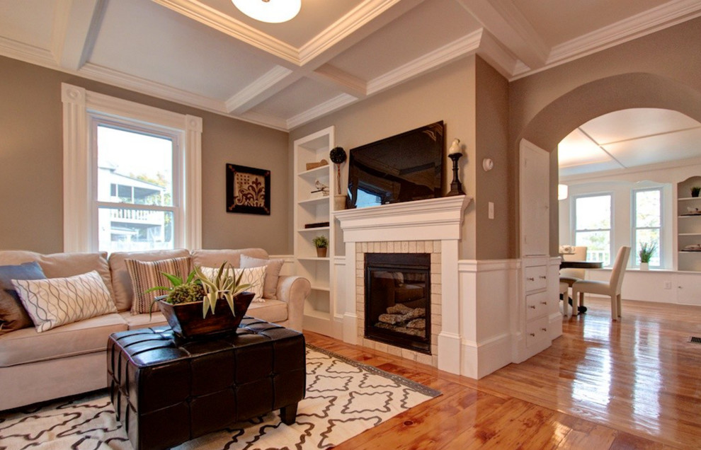 Mittelgroßes, Offenes Klassisches Wohnzimmer mit grauer Wandfarbe, braunem Holzboden, Kamin, Kaminumrandung aus Backstein und TV-Wand in Boston