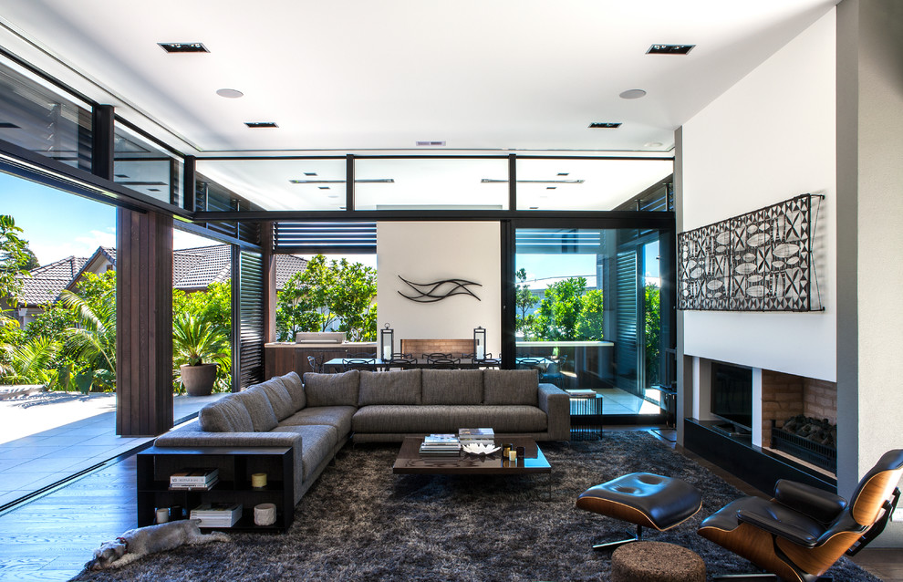 This is an example of a contemporary living room in Auckland with white walls, a standard fireplace and a freestanding tv.
