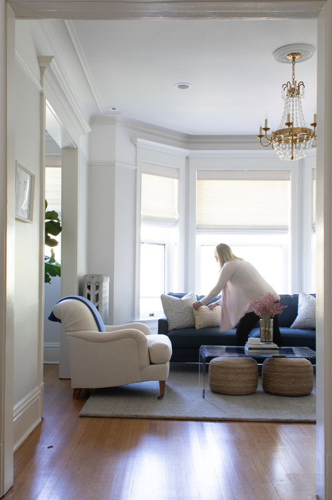 Ispirazione per un soggiorno tradizionale di medie dimensioni con pareti bianche, pavimento in legno massello medio, TV a parete e pavimento marrone