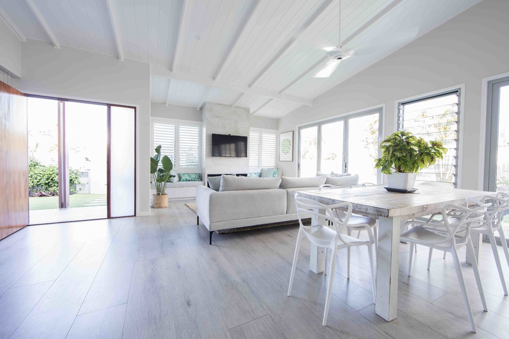 Источник вдохновения для домашнего уюта: открытая гостиная комната среднего размера в морском стиле с белыми стенами, деревянным полом, стандартным камином, фасадом камина из камня и серым полом