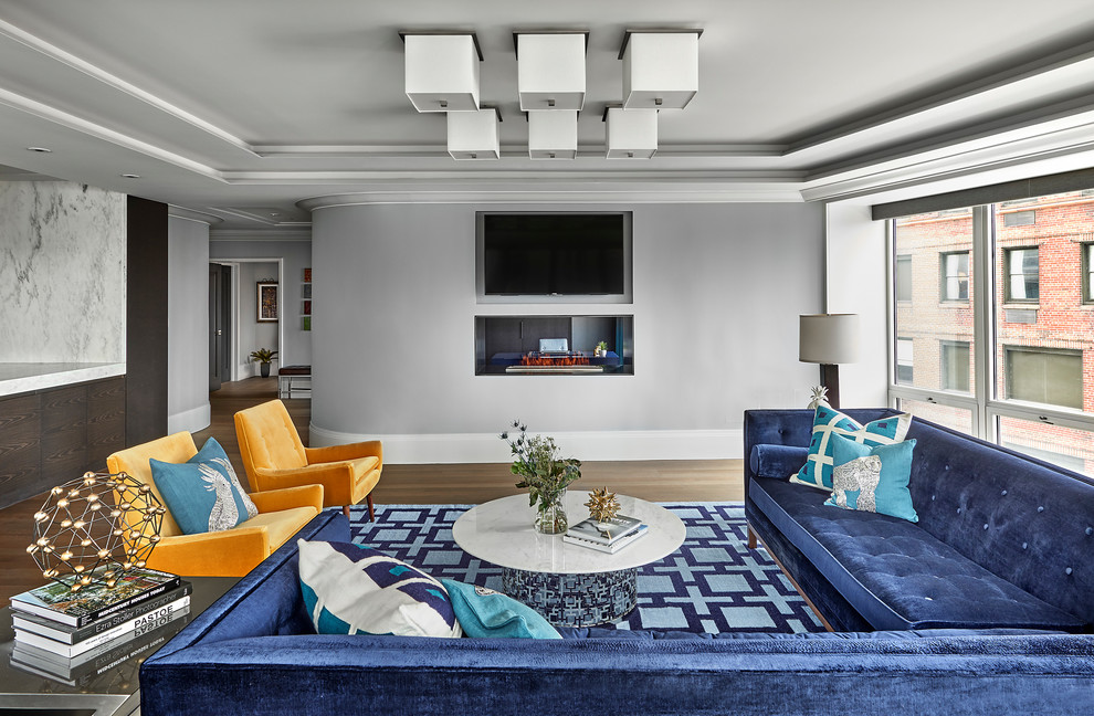 Foto di un soggiorno chic aperto con pareti grigie, pavimento in legno massello medio, camino bifacciale, TV a parete e pavimento marrone