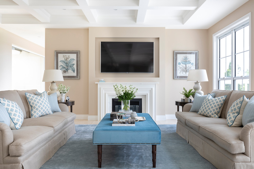 This is an example of a traditional living room in Gold Coast - Tweed with beige walls, a standard fireplace, a wall mounted tv and beige floors.