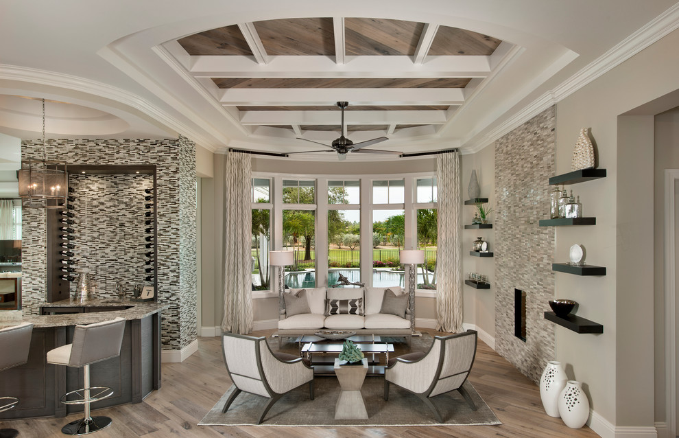 Offenes Klassisches Wohnzimmer mit Hausbar, grauer Wandfarbe, hellem Holzboden und gefliester Kaminumrandung in Miami