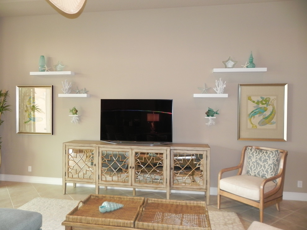 Modelo de salón abierto costero grande con paredes beige, suelo de baldosas de porcelana y televisor colgado en la pared