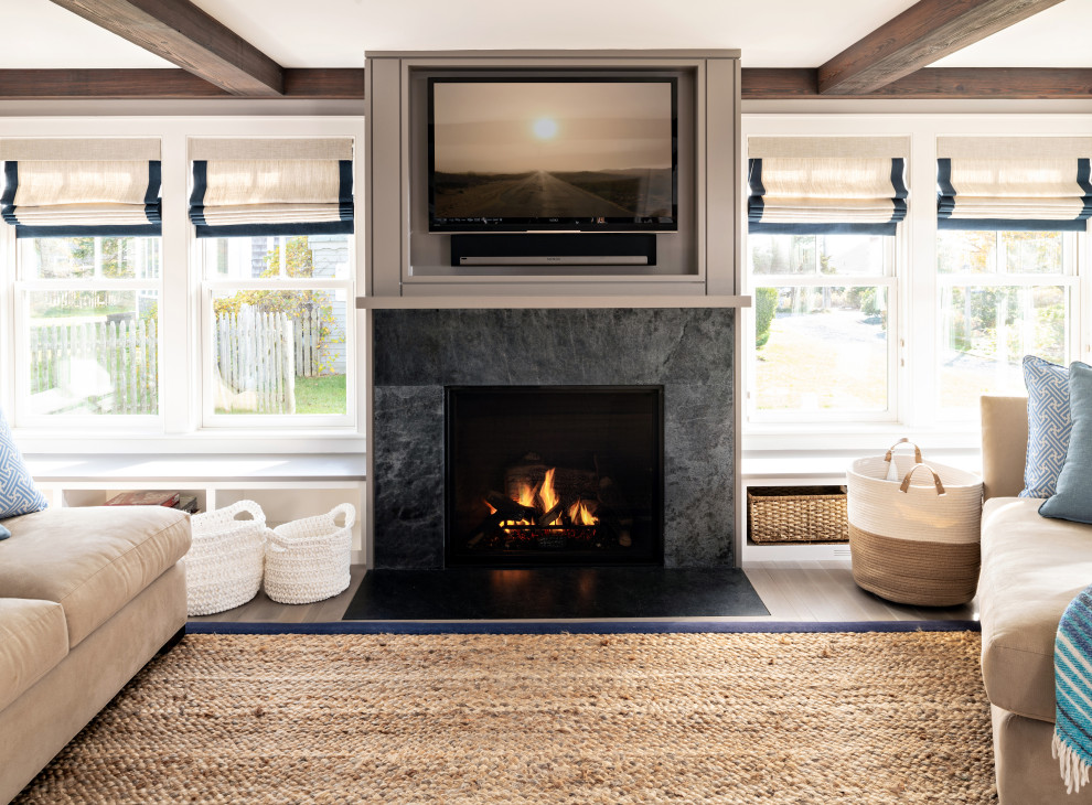 Offenes Maritimes Wohnzimmer mit grauer Wandfarbe, braunem Holzboden, Kamin, TV-Wand, braunem Boden und freigelegten Dachbalken in Boston