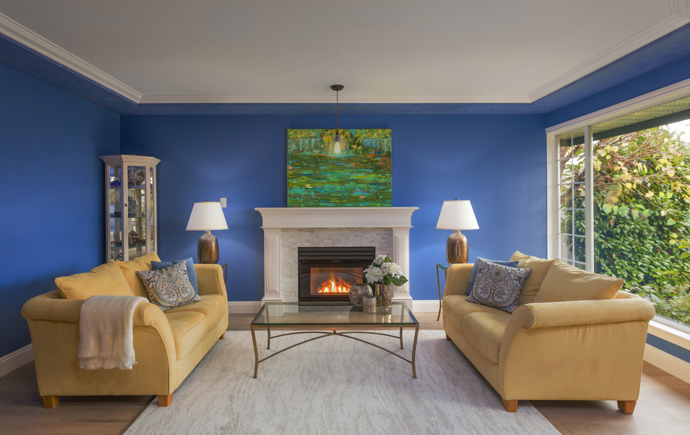 Inspiration för mellanstora klassiska separata vardagsrum, med ett finrum, blå väggar, en standard öppen spis, en spiselkrans i sten, brunt golv och ljust trägolv