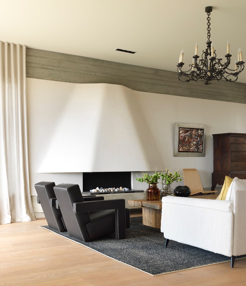 Cette image montre un grand salon design avec un mur blanc, un sol en bois brun et une cheminée ribbon.