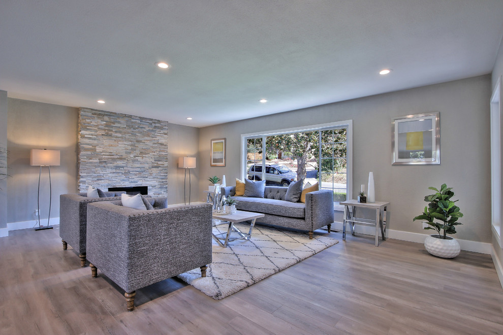 Large contemporary open plan living room in San Francisco with grey walls, laminate floors, a ribbon fireplace, a stone fireplace surround, no tv and grey floors.