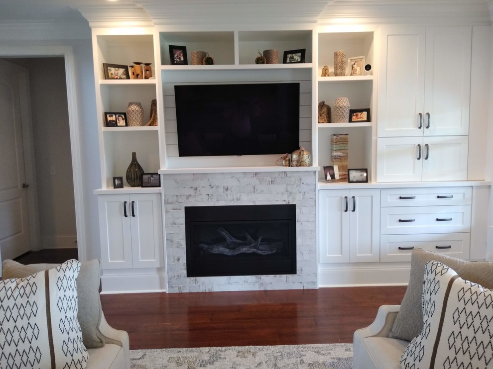 Cette image montre un grand salon design ouvert avec un mur blanc, un sol en bois brun, une cheminée standard, un manteau de cheminée en carrelage, un téléviseur fixé au mur et un sol marron.