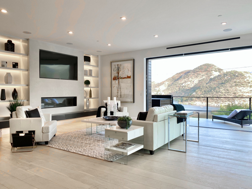 Idées déco pour un salon contemporain ouvert avec un mur blanc, parquet clair, une cheminée standard, un téléviseur encastré et un sol gris.