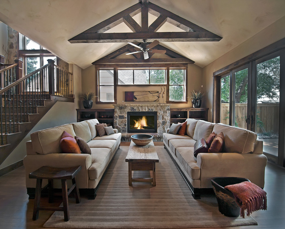 This is an example of a rustic living room in Denver with beige walls, a standard fireplace and a stone fireplace surround.