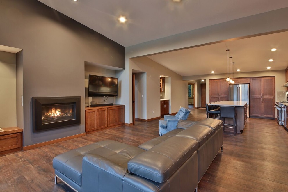 Mid-sized minimalist open concept dark wood floor living room photo in Seattle with beige walls, a standard fireplace, a plaster fireplace and a wall-mounted tv