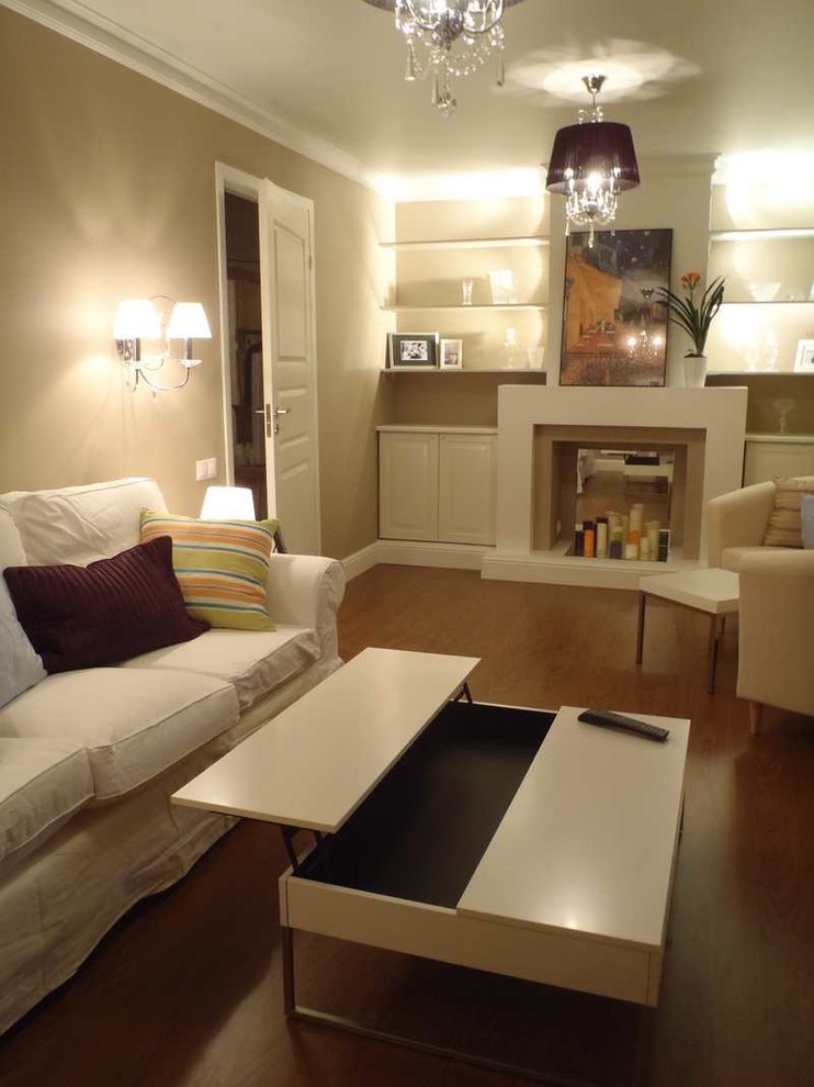 Foto de biblioteca en casa cerrada, contemporánea, pequeña, con paredes beige, suelo laminado, todas las chimeneas, marco de chimenea de yeso, televisor independiente y suelo marrón